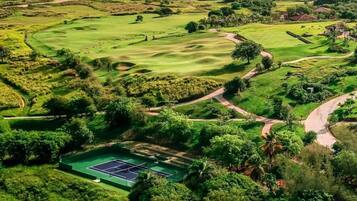 Luftaufnahme eines Golfplatzes mit Tennisplatz und umliegender Grünfläche.
