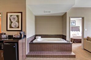 A modern bathroom with a freestanding bathtub, a coffee machine, and a refrigerator.