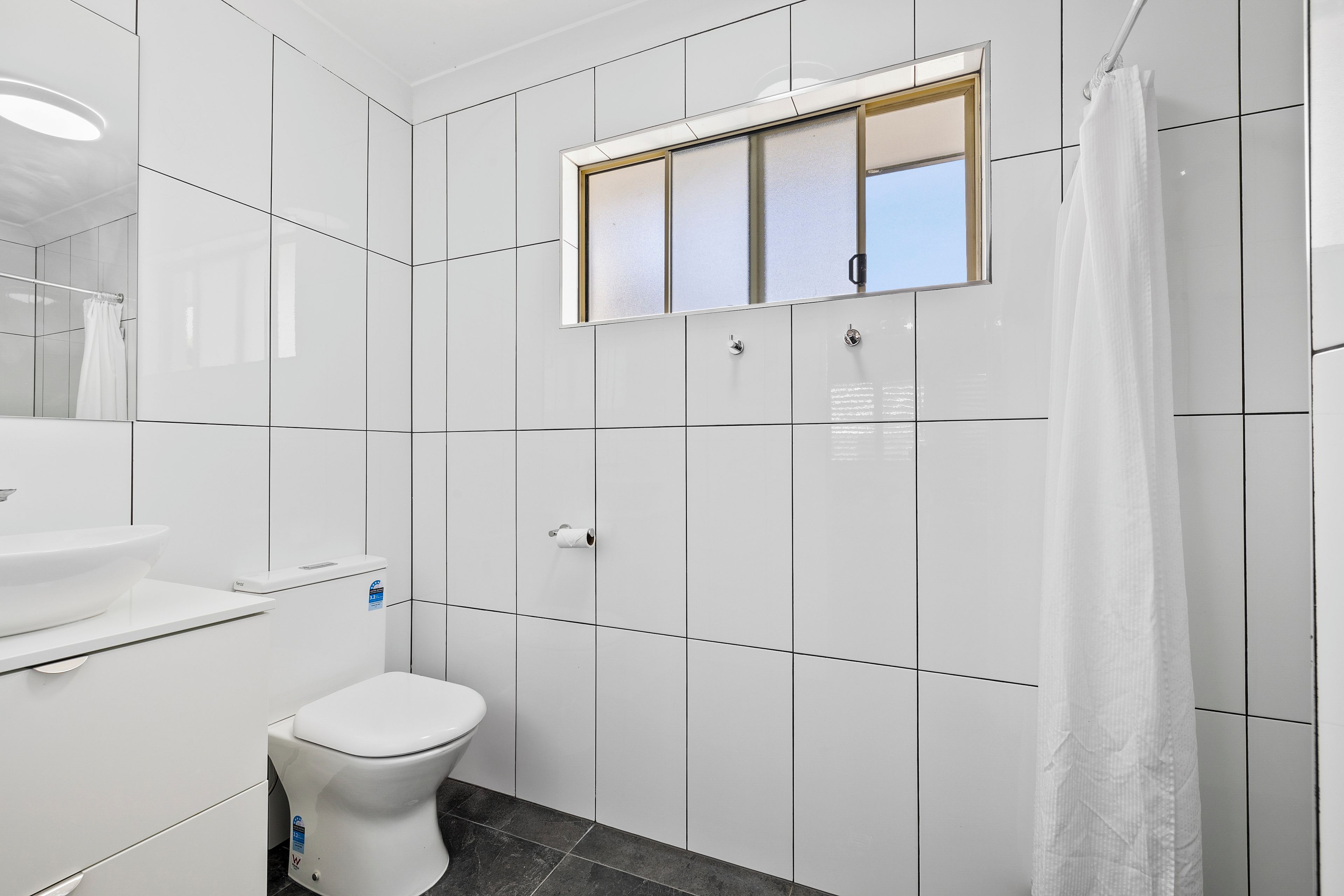 A modern bathroom with a toilet, sink, and a shower curtain.