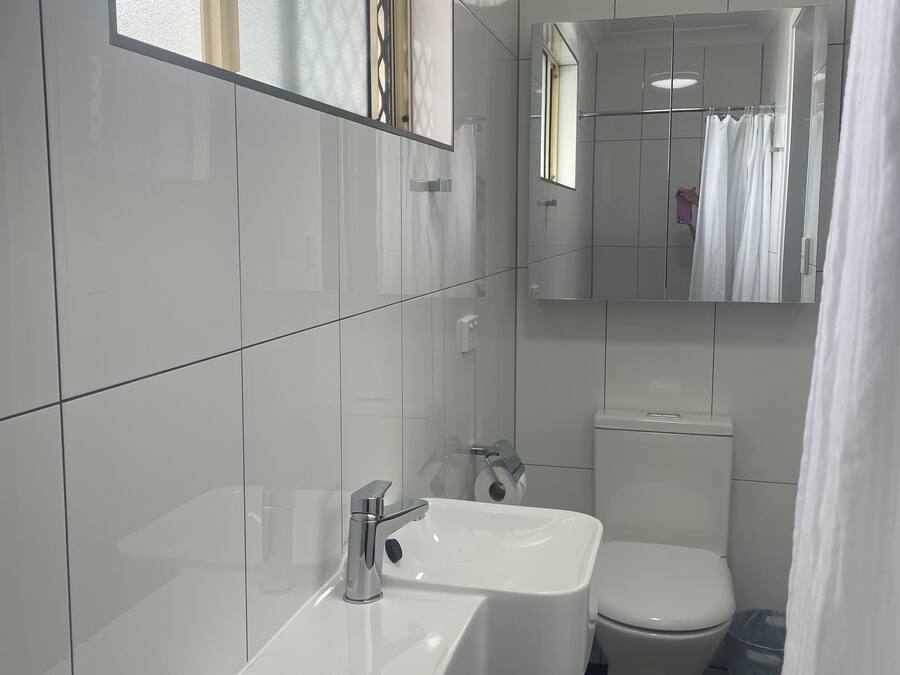 Un baño moderno con lavamanos, espejo y retrete blancos.