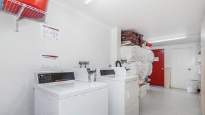 Un cuarto de lavandería con dos lavadoras blancas, una puerta roja y una pila de toallas dobladas.
