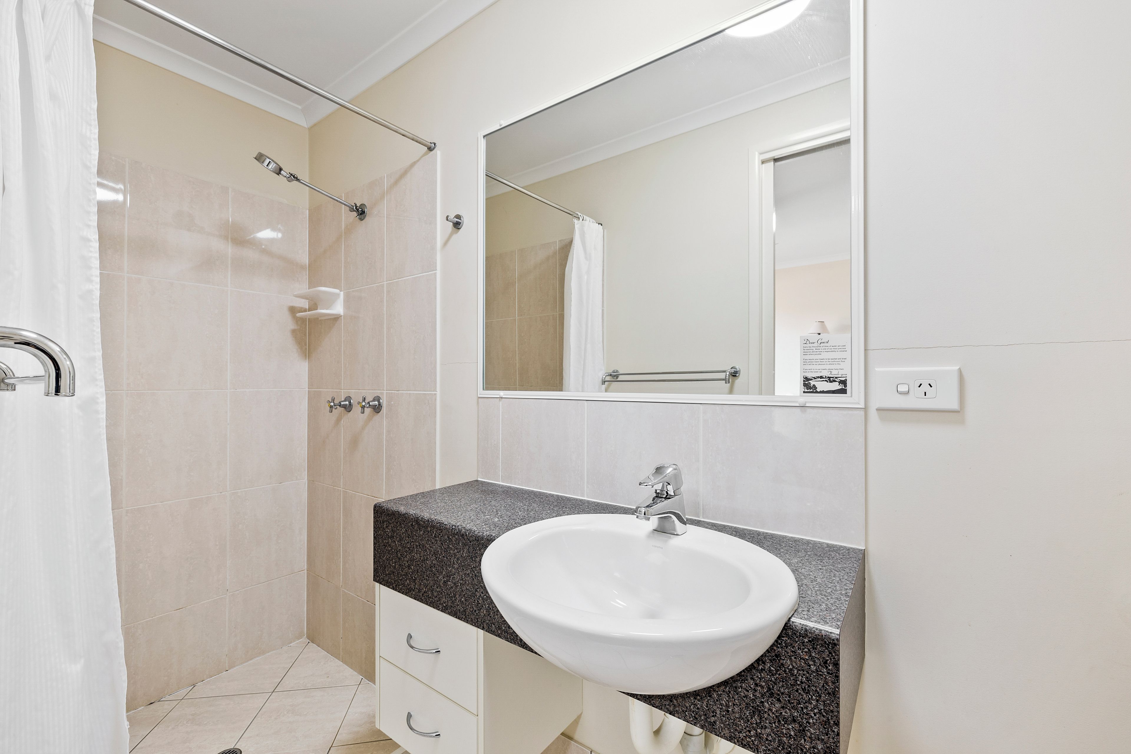 Un baño moderno con ducha, lavamanos y espejo.