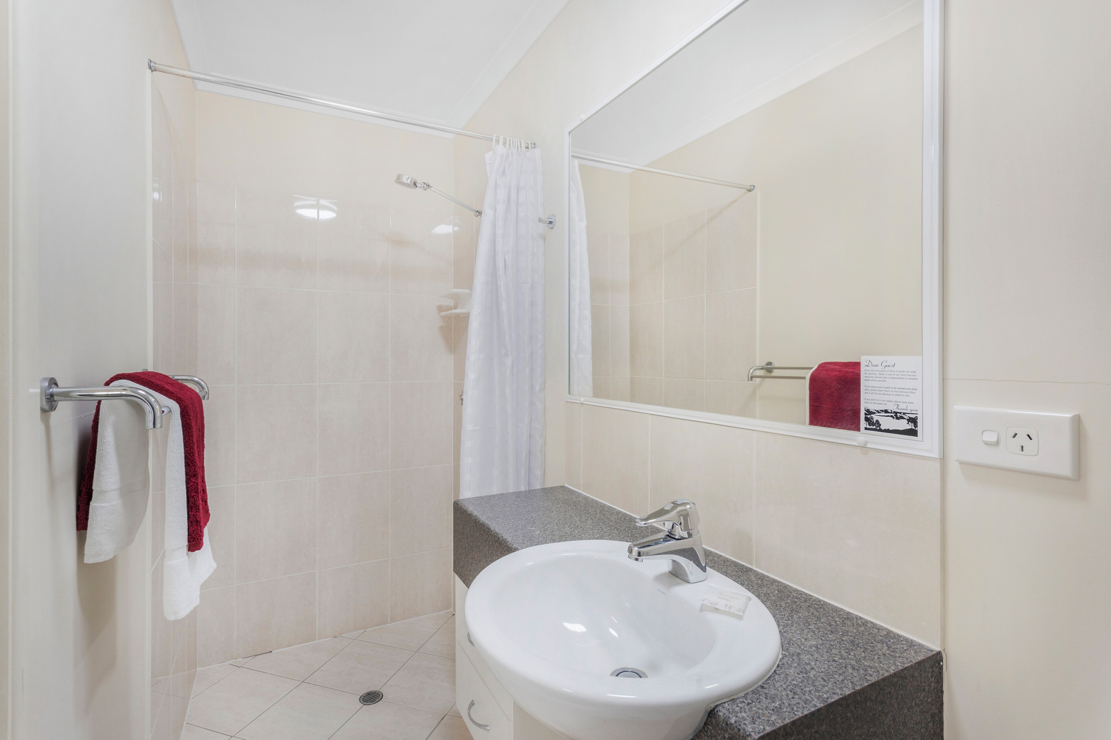 A bathroom with a glass shower enclosure, a white sink, and a mirror.