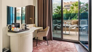 A hotel room with a curved white desk, a beige chair, a large sliding glass door leading to an outdoor patio with a table and chairs. - Hotel Indigo Barcelona - Plaza Catalunya by IHG (Barcelona)