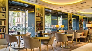 A modern library with round tables and chairs, bookshelves, and a view of the street outside. - Hotel Indigo Barcelona - Plaza Catalunya by IHG (Barcelona)