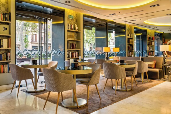 Une bibliothèque moderne avec des tables et des chaises rondes, des étagères et une vue sur la rue.