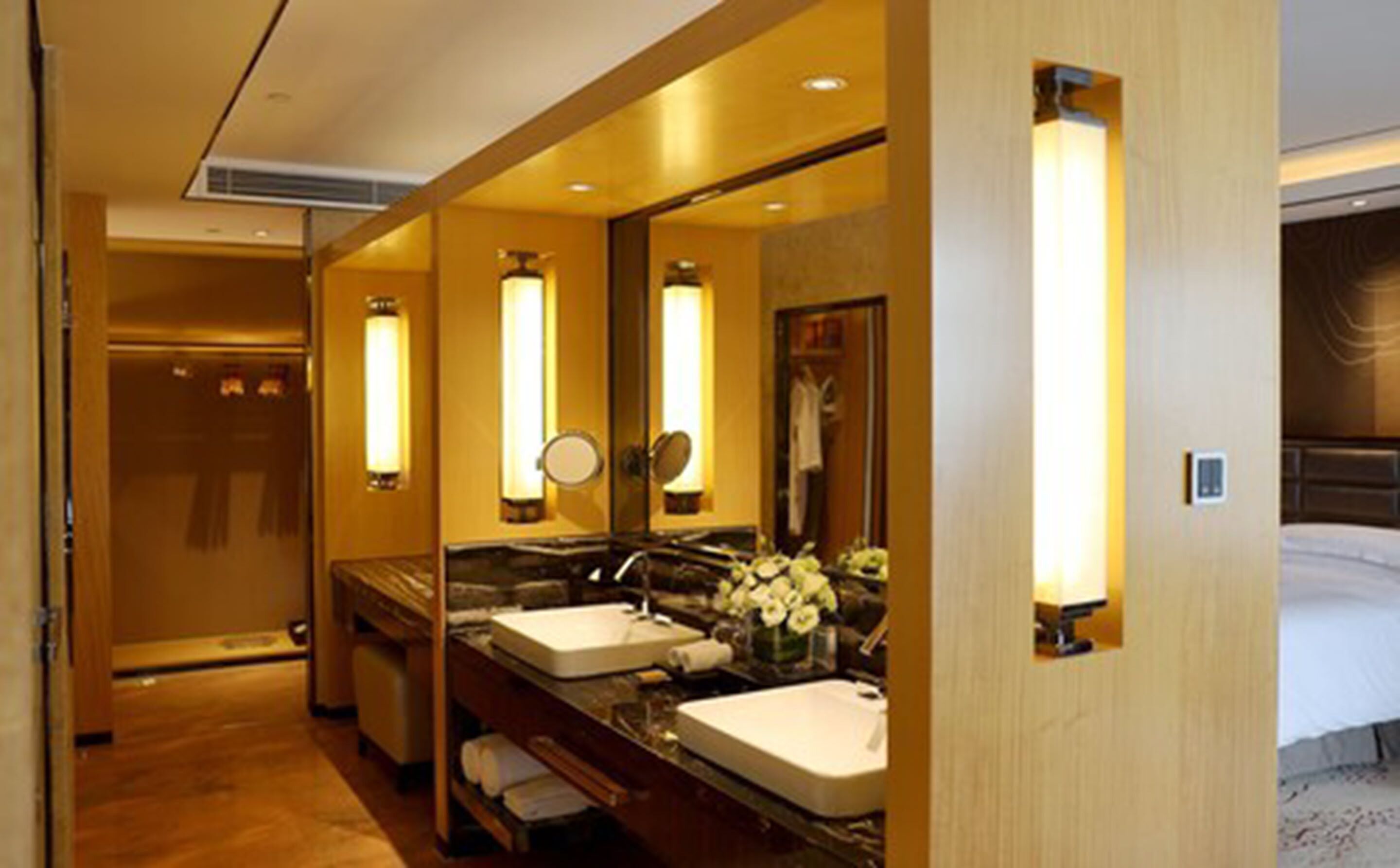 A hotel bathroom with two sinks, a mirror, and a shower area.