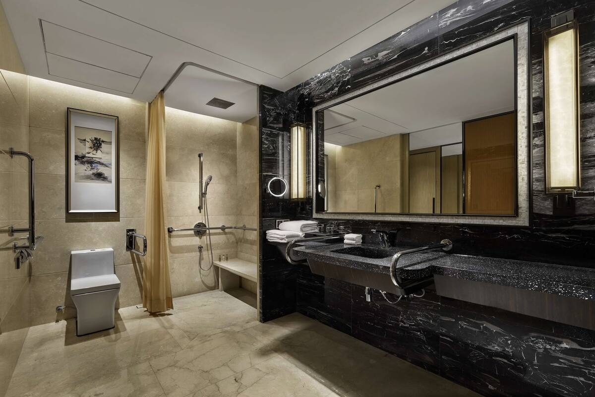 Un baño moderno con un espejo grande, zona de ducha e inodoro.