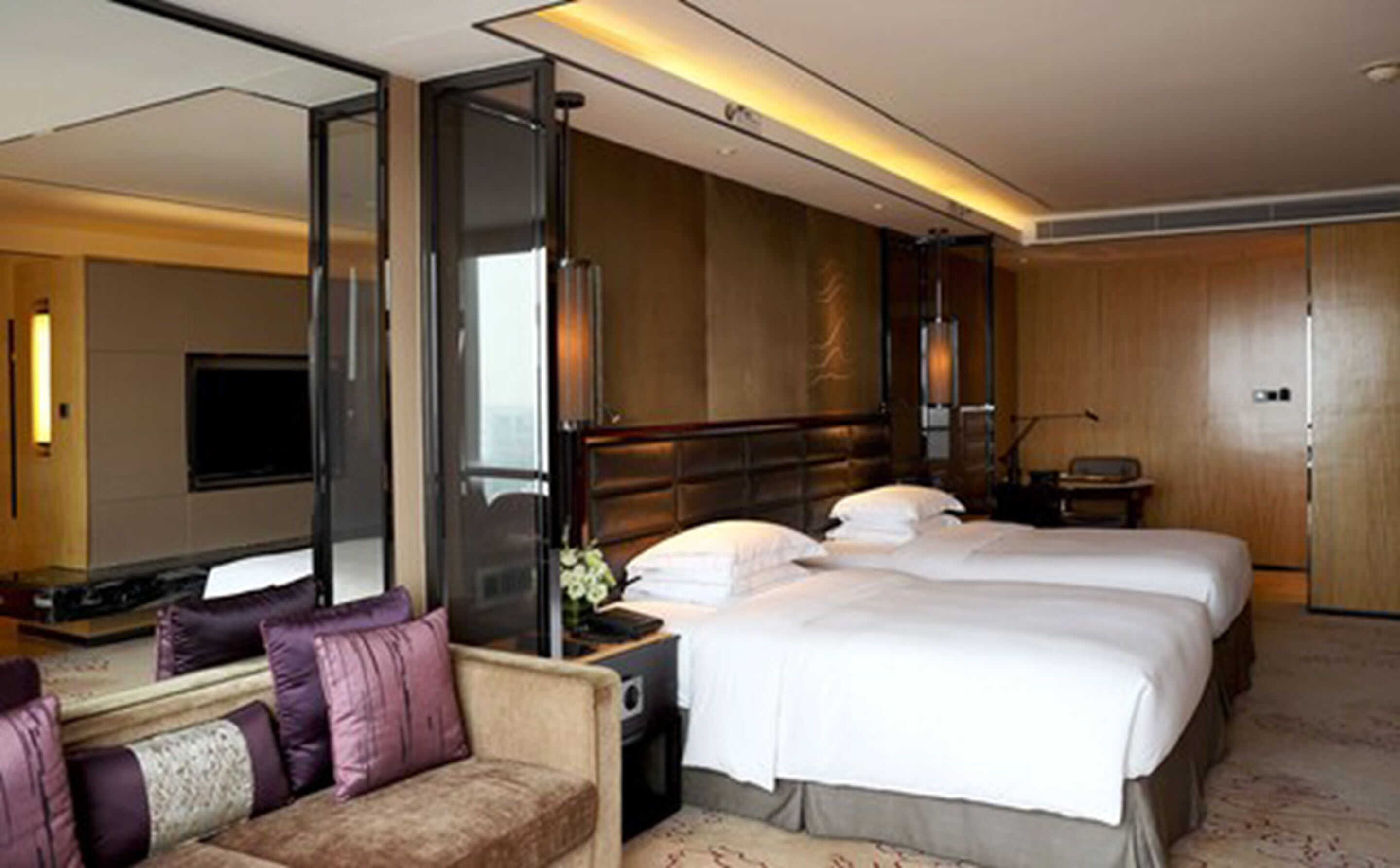 Ein Hotelzimmer mit zwei Betten, einem Sofa, einem Schreibtisch und einem großen Spiegel.