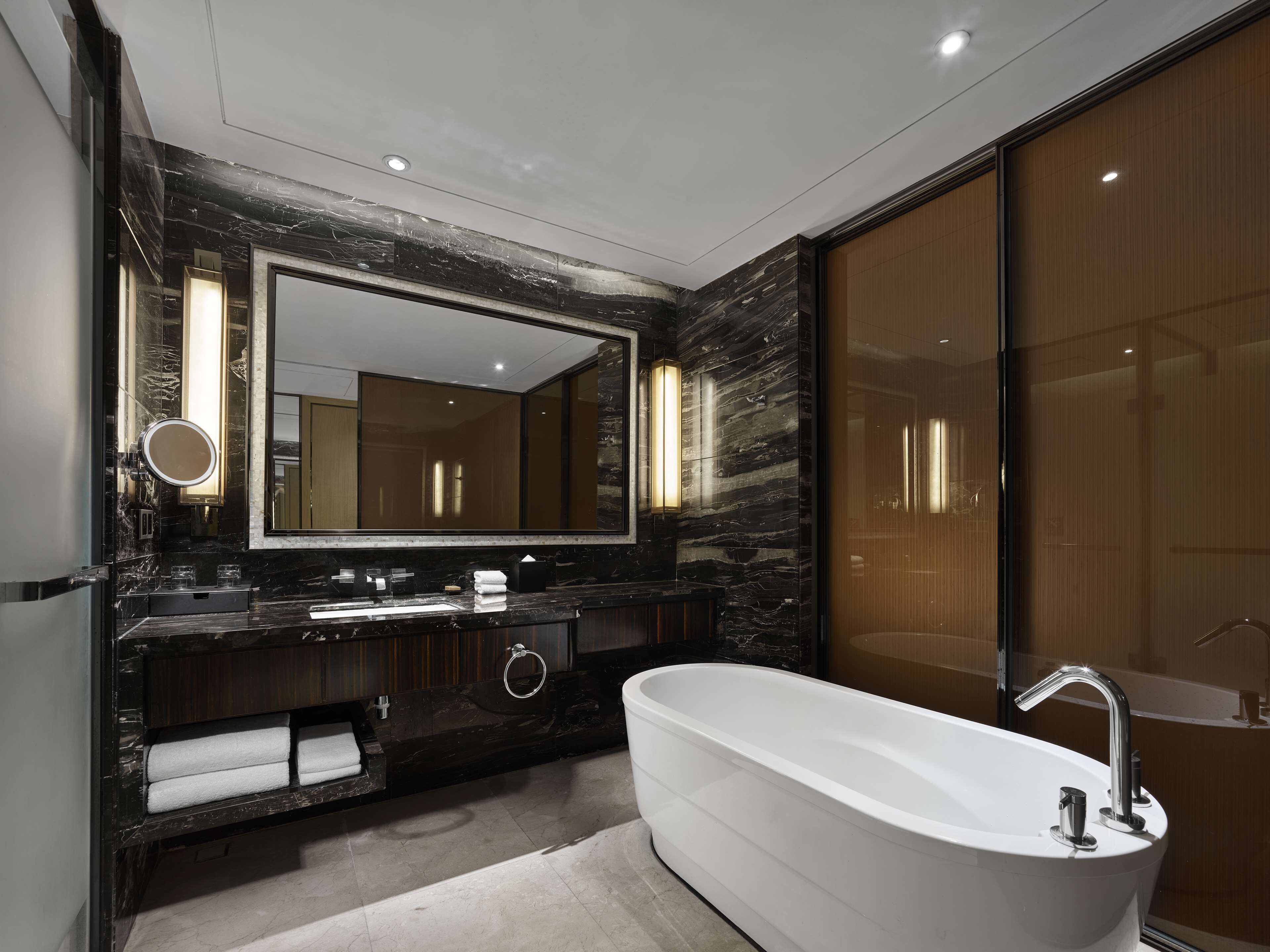 A modern bathroom with a large freestanding bathtub, a double vanity with a mirror, and a large mirror above the sink.