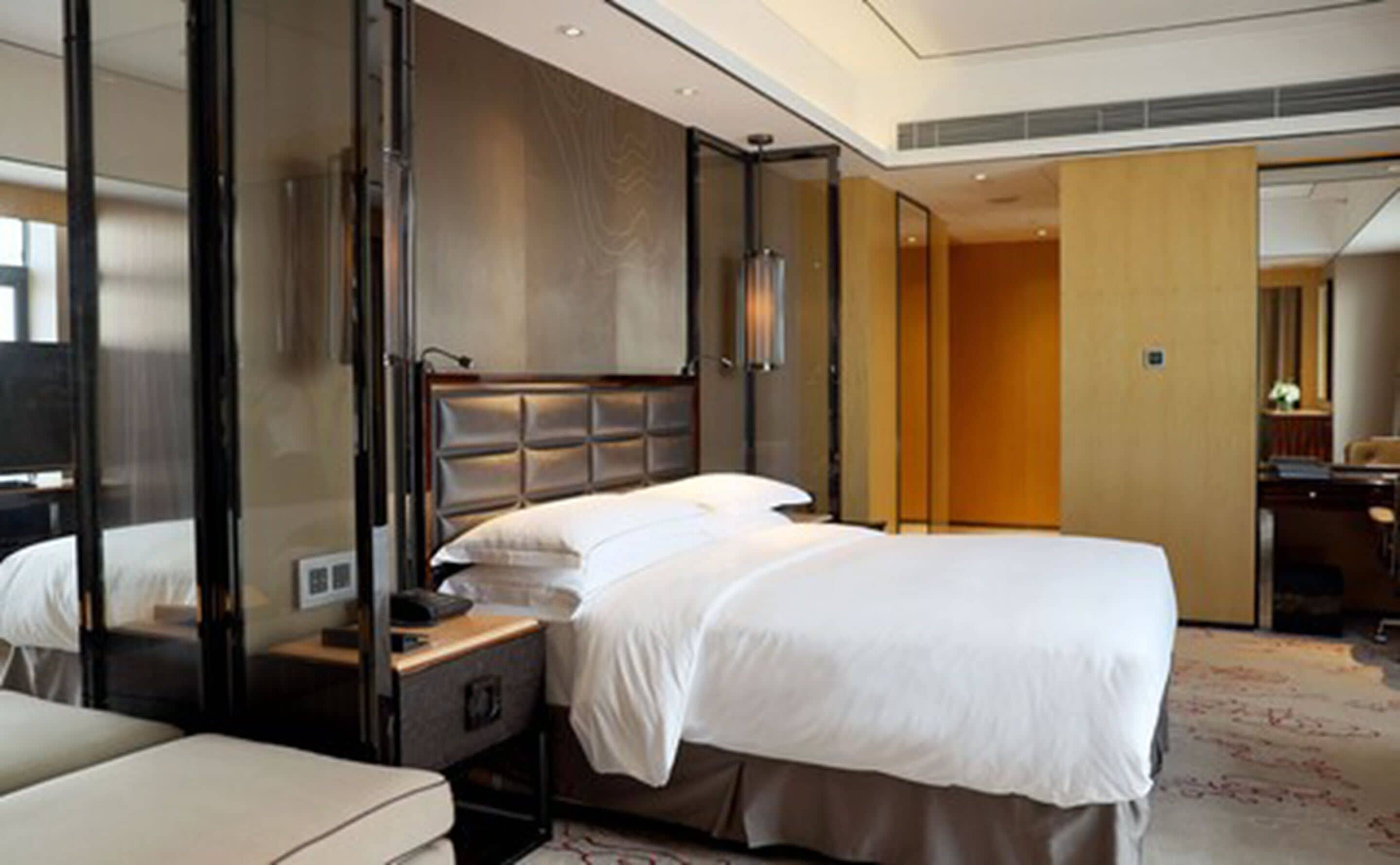 Habitación de hotel con una cama grande, una mesita de noche, un espejo y un armario.