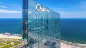 A modern glass building with the name 'Ocean' on its facade, overlooking a beach and the ocean. - Ocean Casino Resort (Atlantic City)
