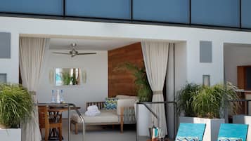 Un área de piscina moderna al aire libre con sillones de descanso, una mesa y un ventilador de techo.