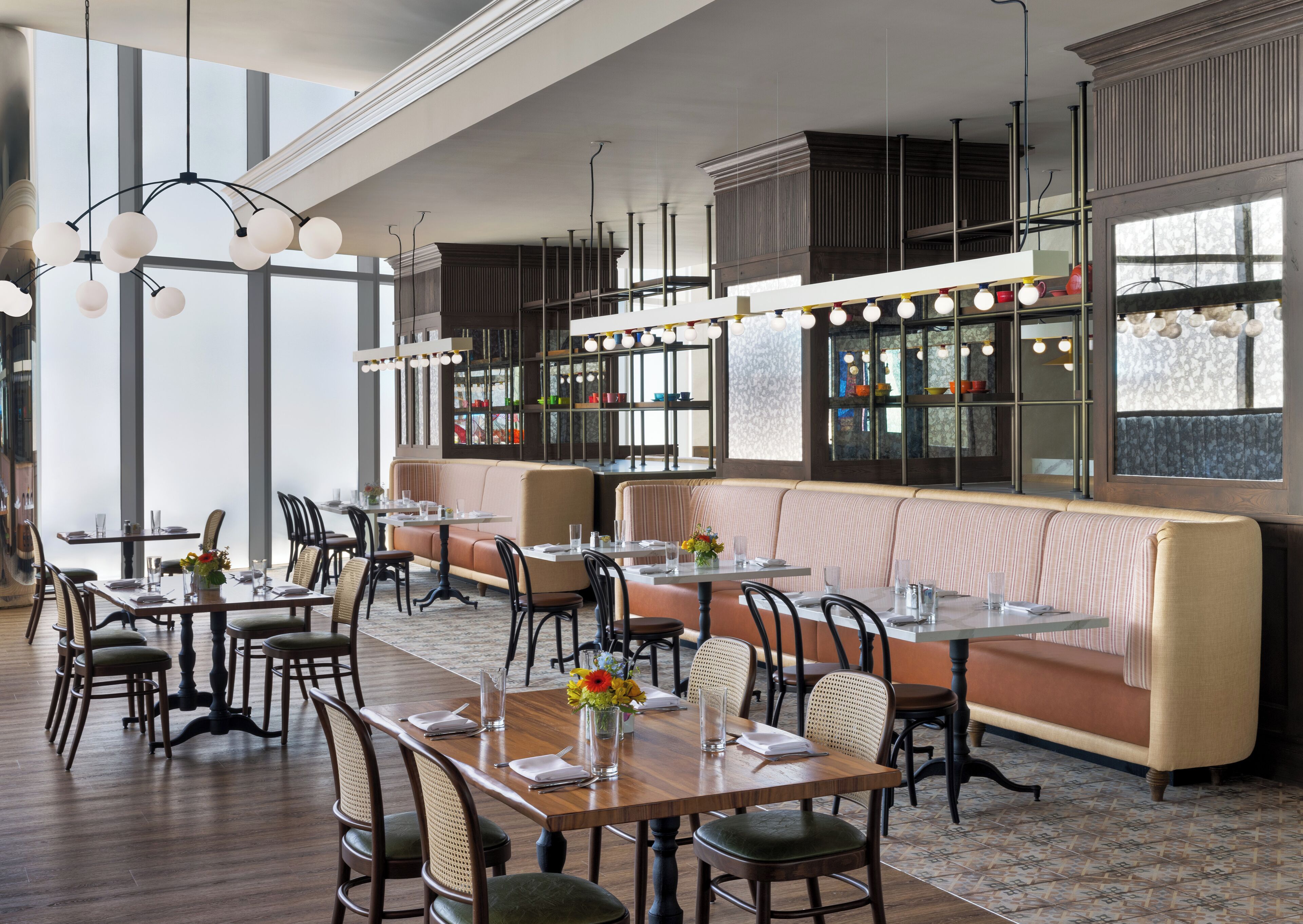 A restaurant with high ceilings, pendant lighting, and a mix of booth and table seating.