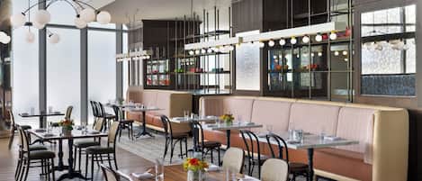 Ein Restaurant mit hohen Decken, Pendelleuchten und einer Mischung aus Sitzecken und Tischen.