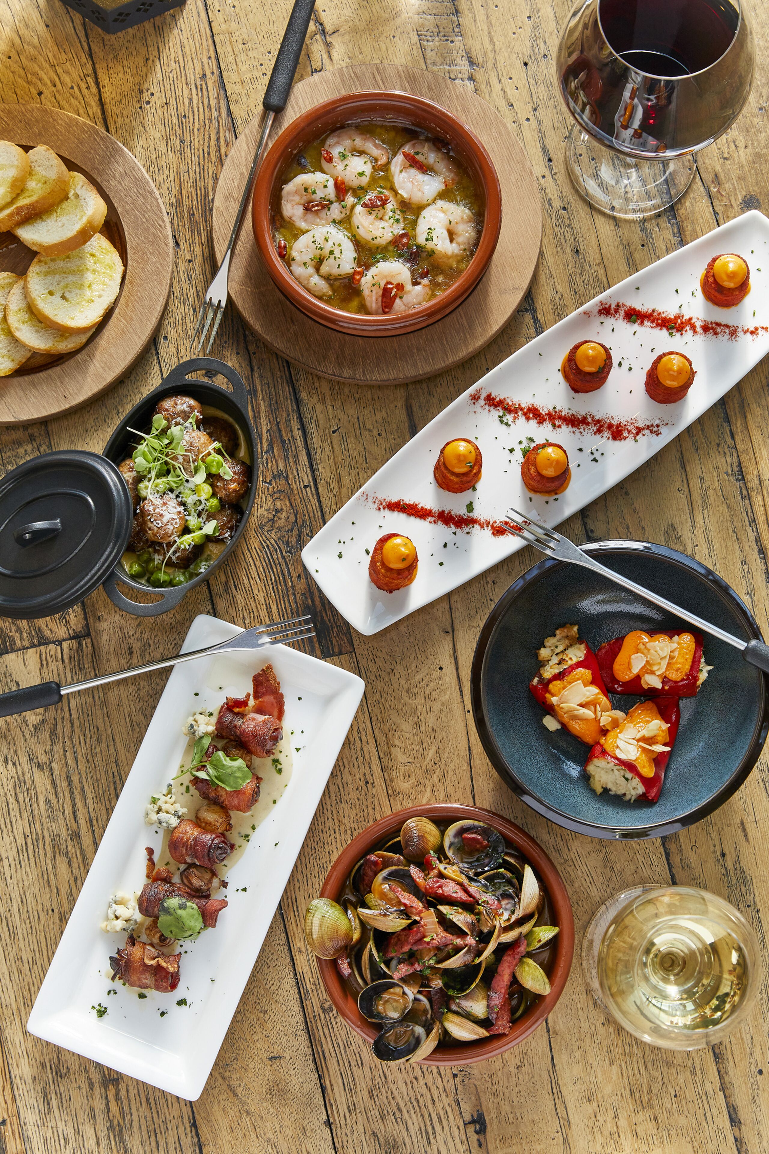 A wooden table with various dishes, including seafood, bread, and a wine glass.