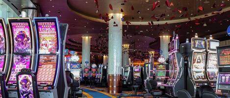 A casino interior with slot machines, a blue carpeted walkway, and red hanging decorations.