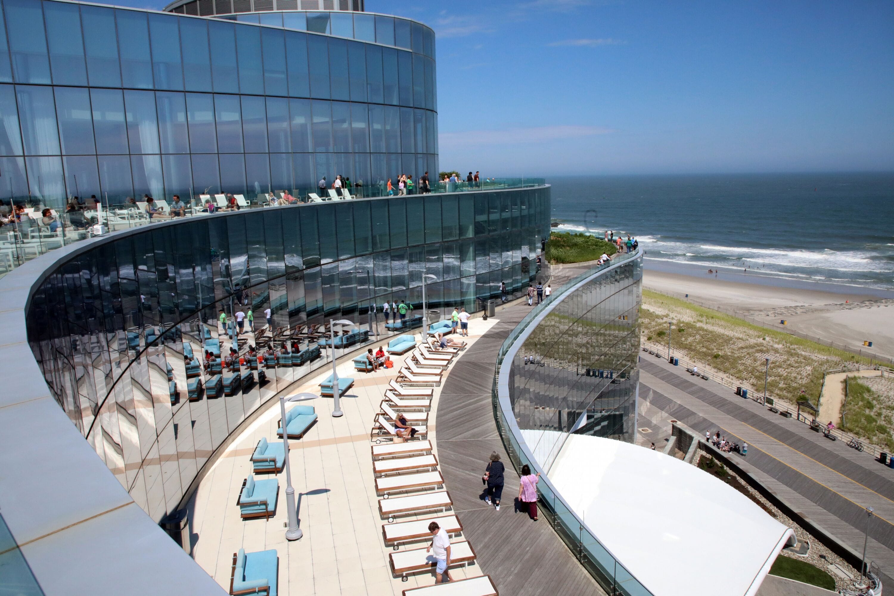 Et moderne hotel med en buet glasfacade med udsigt over stranden.