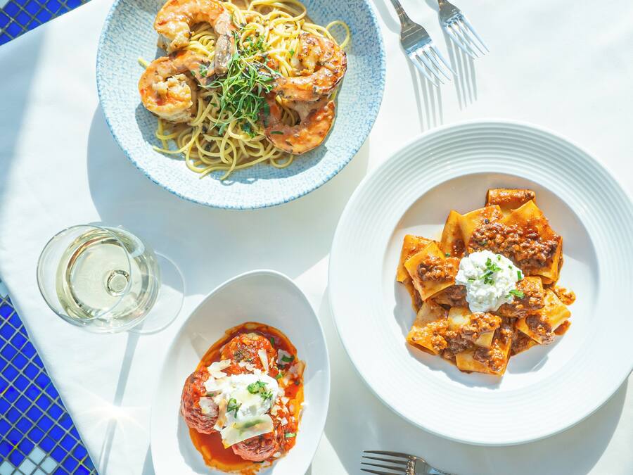 Three plates of pasta dishes on a table.