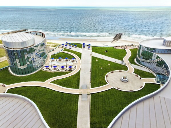 Un edificio moderno con diseño circular, un césped central y vistas al océano.