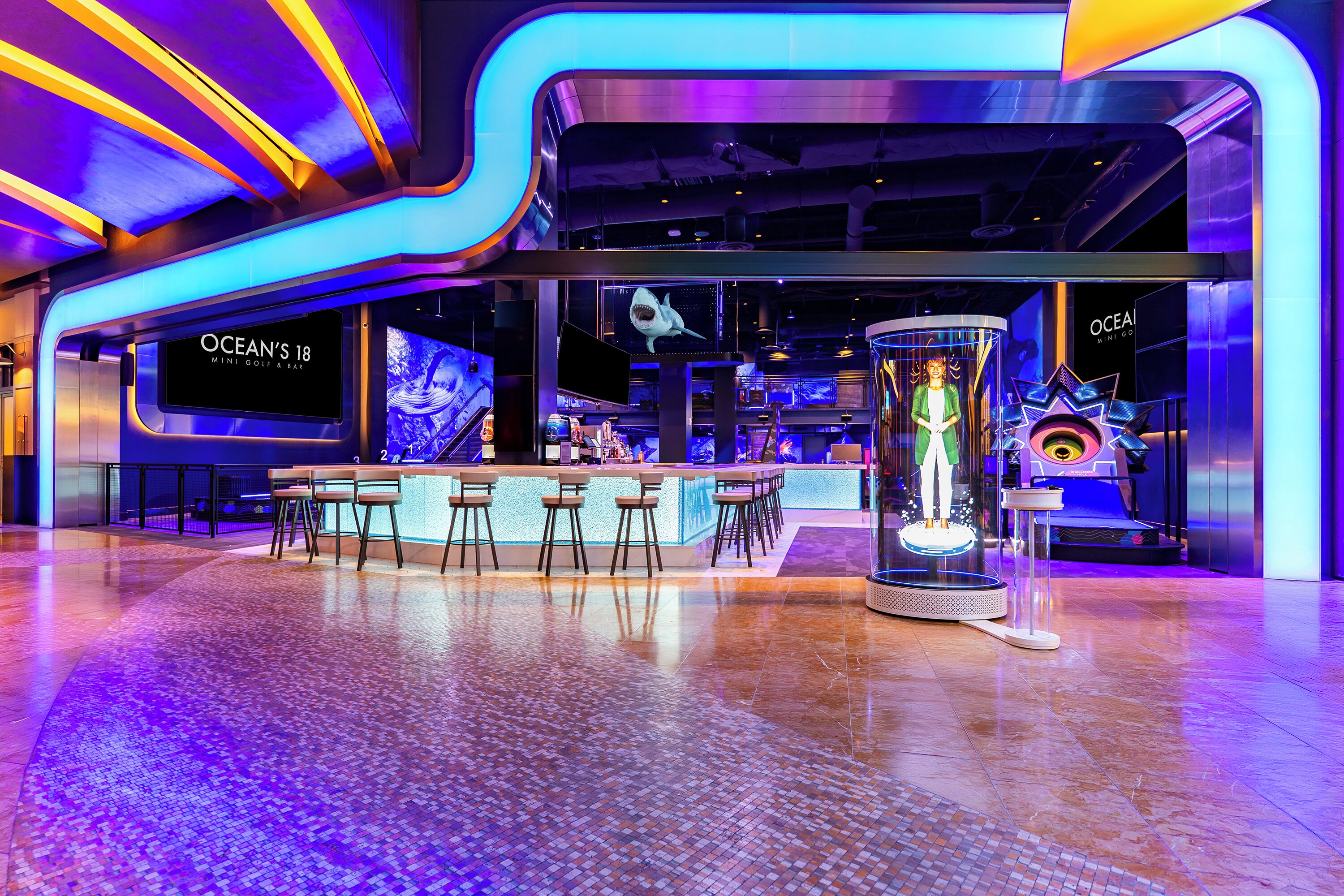 A modern bar area with a counter, bar stools, and a large screen displaying a shark.