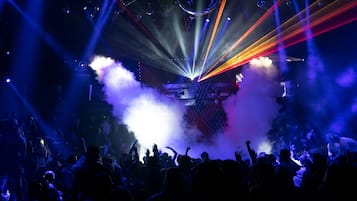 A crowded indoor event with a stage, smoke effects, and a crowd of people.
