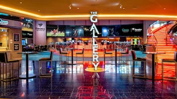 A spacious hotel lobby with a central bar area, multiple seating arrangements, and a prominent 'The Gallery' sign.