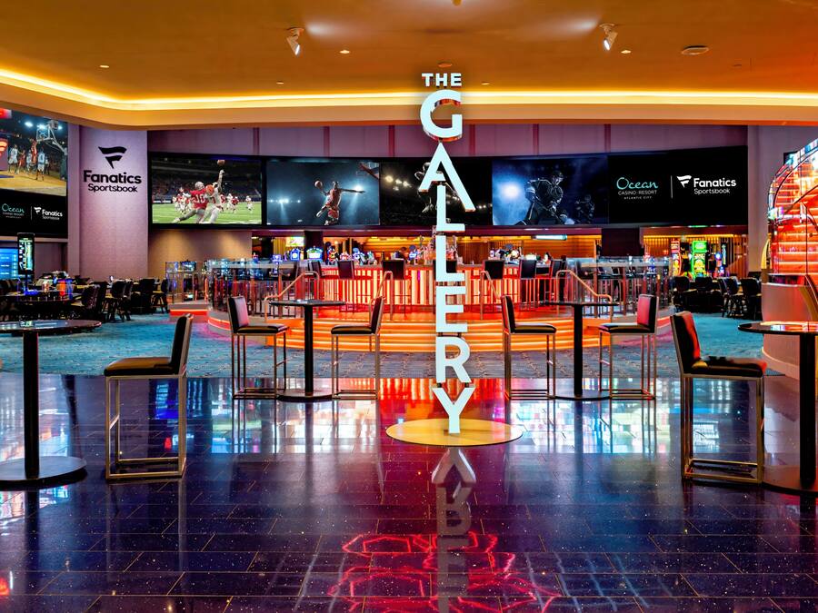 A spacious hotel lobby with a central bar area, multiple seating arrangements, and a prominent 'The Gallery' sign.