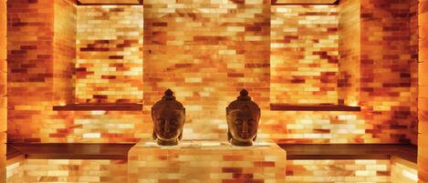 A room with a tiled wall, two statues, and a bench.
