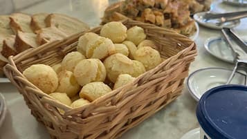 Een buffet met diverse gerechten, waaronder broodbaskets, een botervlaai en een bord met een rode hap.