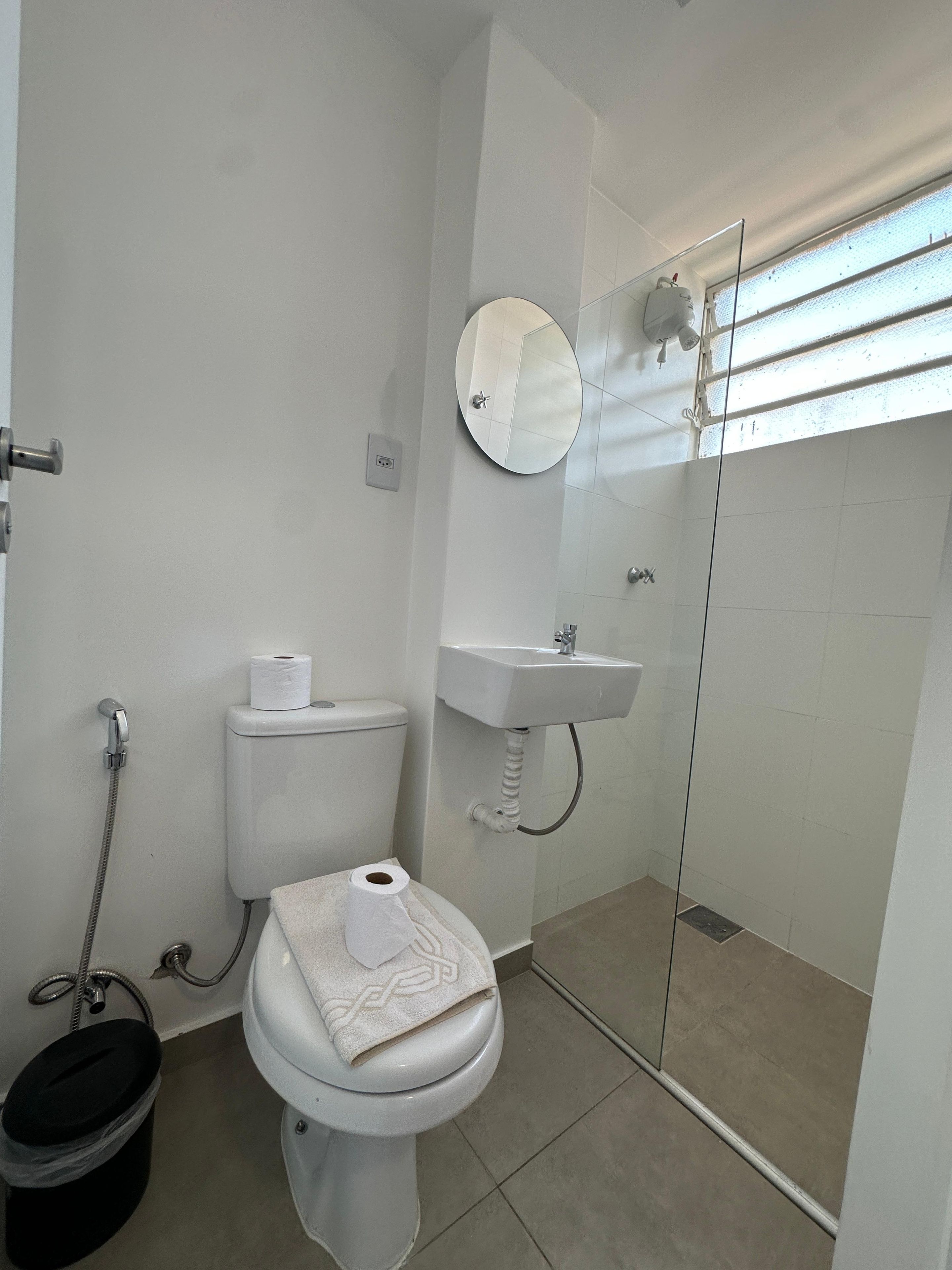 A bathroom with a toilet, a sink, a shower, and a mirror.