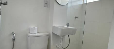 Un baño con inodoro, lavabo, ducha y espejo.