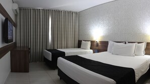 Une chambre d’hôtel avec deux lits, une télévision, un bureau et une fenêtre avec des rideaux.