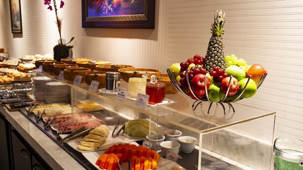 Un buffet proposant une variété de plats, notamment des fruits, des légumes et des desserts.