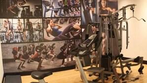 Une salle de sport équipée de divers appareils d’exercice, notamment un tapis de course et des appareils de musculation.