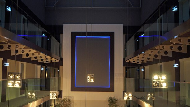 A modern atrium with a glass ceiling, potted plants, and a patterned floor.
