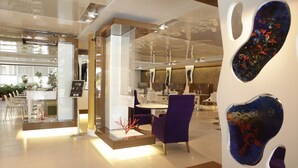A modern interior with a reception desk, seating area, and a dining space.