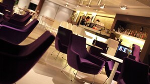 A modern bar area with purple chairs and a counter.