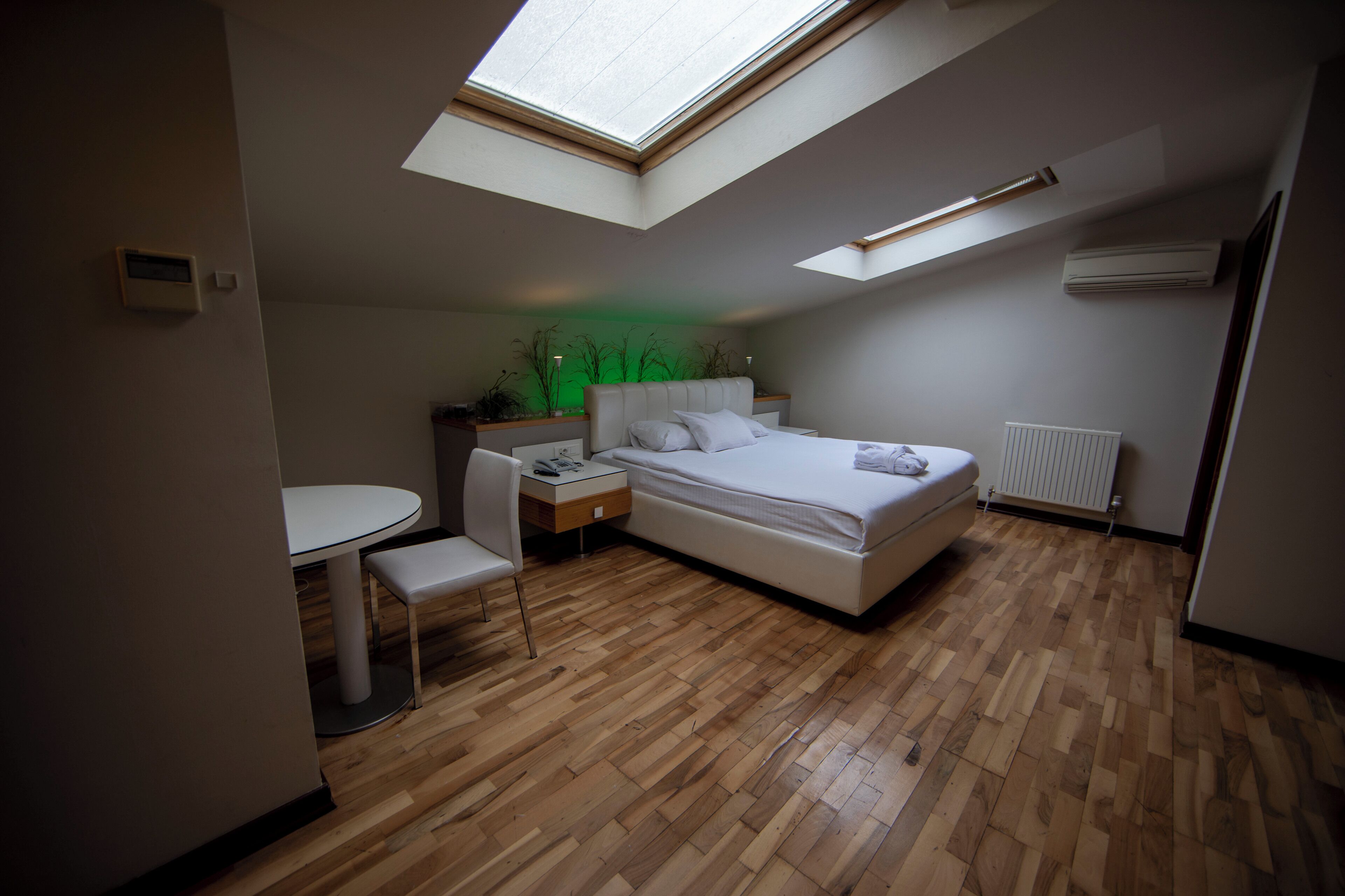 Un dormitorio con tragaluz, una cama, un escritorio y una silla.