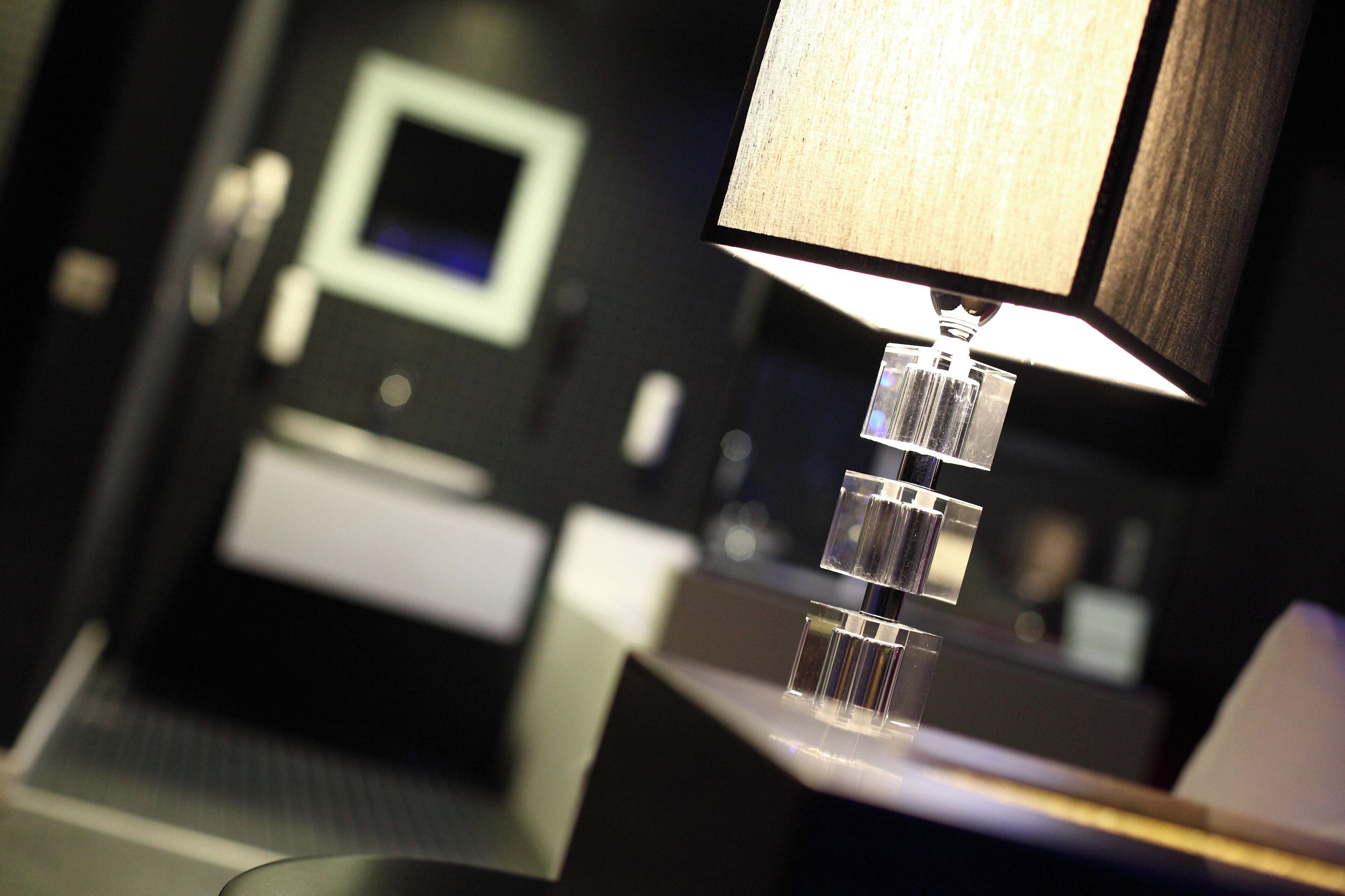 A modern hotel room with a desk, a lamp, and a mirror.