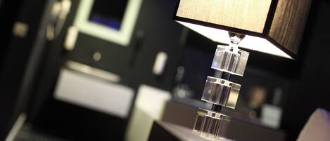 A modern hotel room with a desk, a lamp, and a mirror.