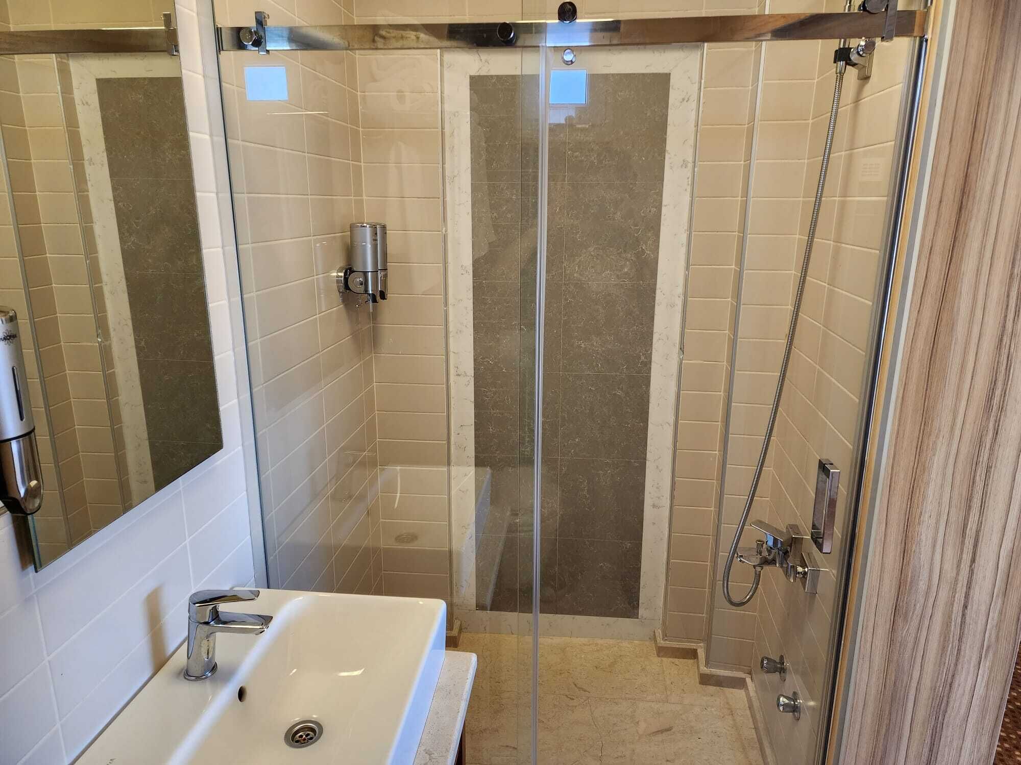A modern bathroom with a glass-enclosed shower, a sink, and a mirror.