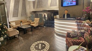 Eine moderne Hotelhalle mit Empfangstresen, Sitzgelegenheit und einem großen Bildschirm, der eine schöne Aussicht zeigt.