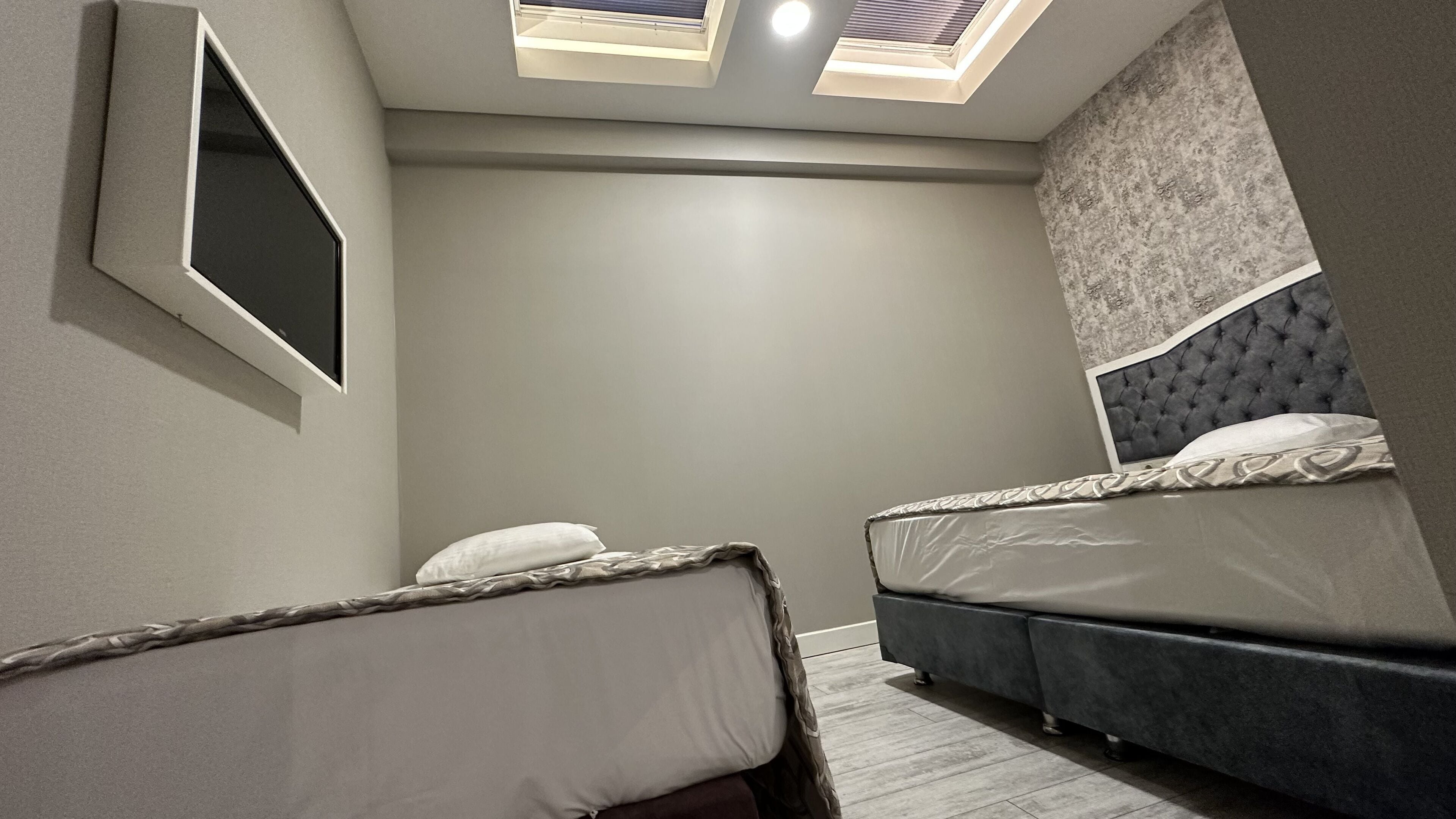 Une chambre avec deux lits, un grand miroir et des fenêtres de toit.