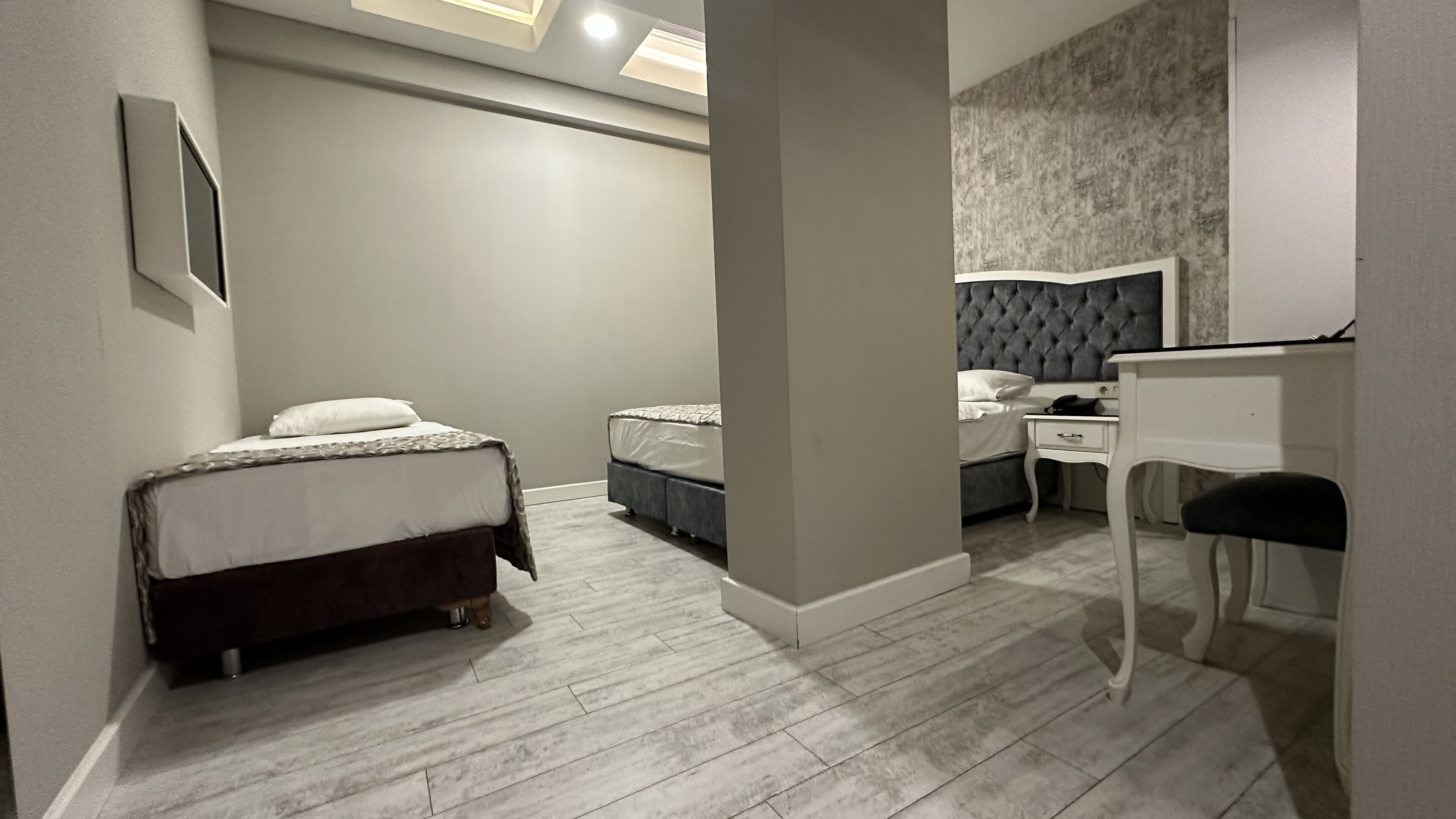 A modern bedroom with two beds, a desk, and a chair.