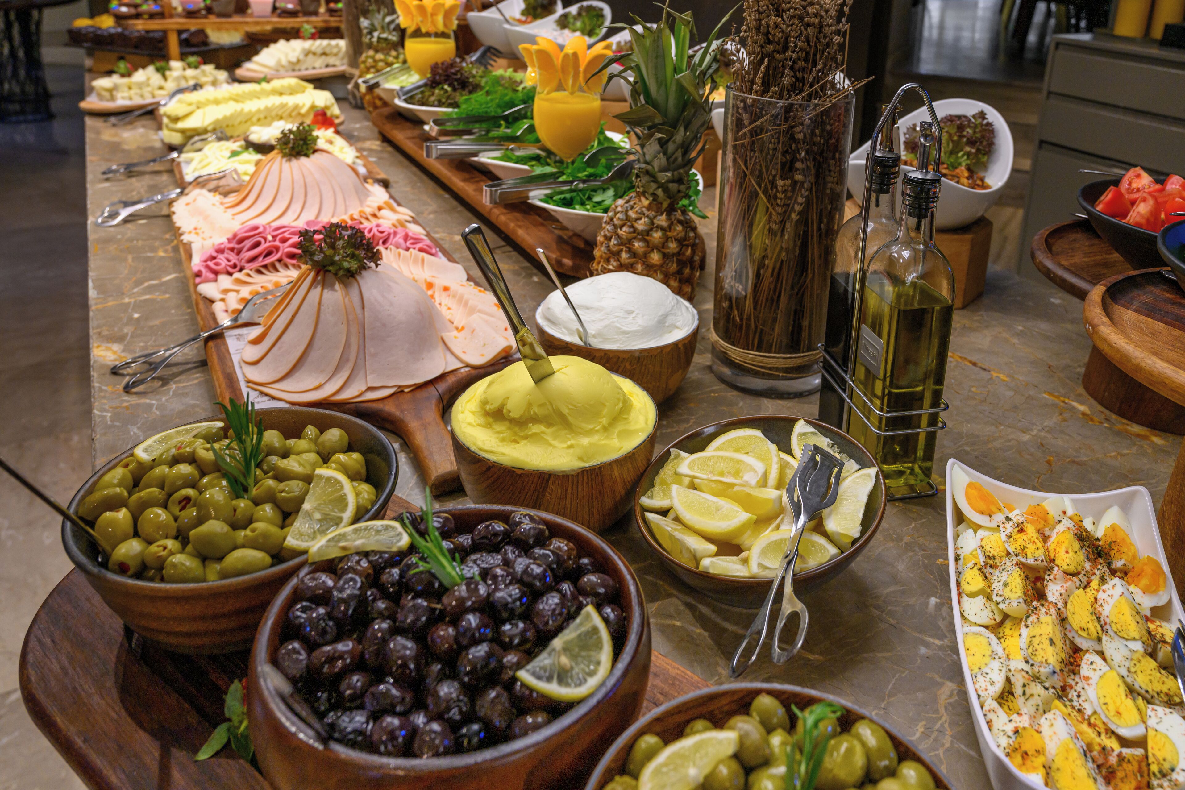 A buffet with various food items including olives, cheese, and meats.