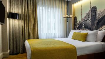 Una habitación de hotel con una cama grande, un televisor en la pared y un cuadro de un paisaje urbano.