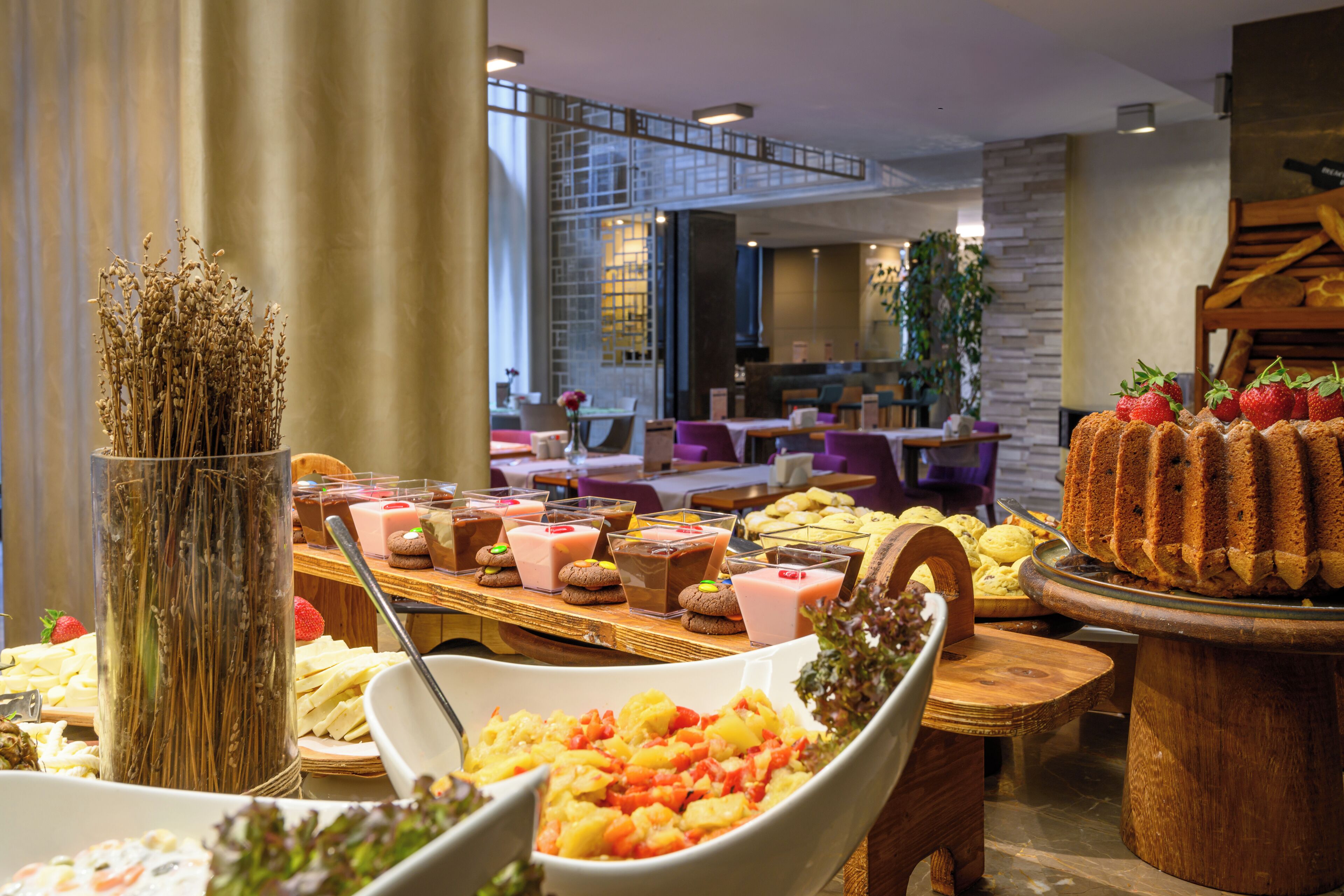 Un bufé con diversos alimentos y un jarrón decorativo de plantas secas.