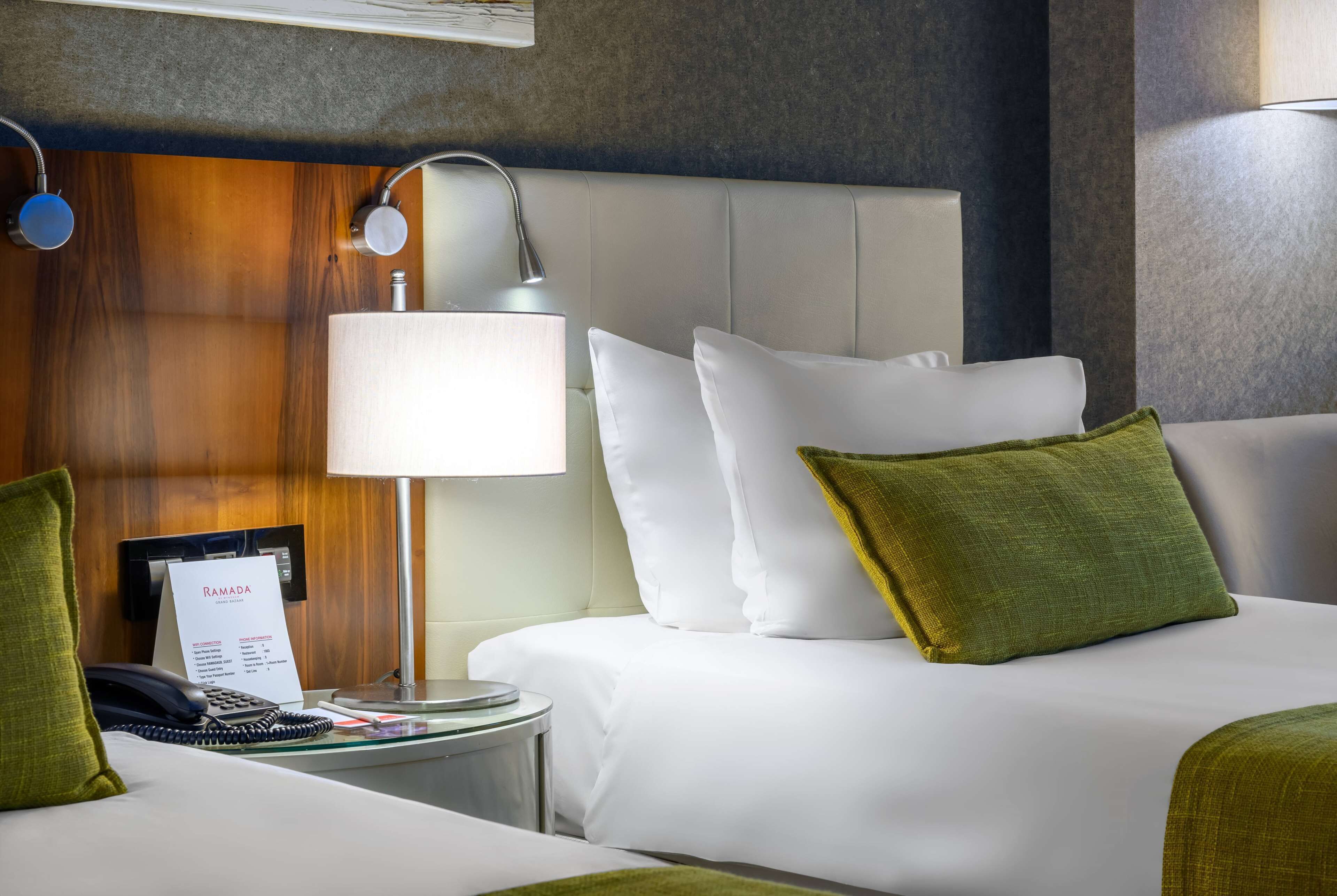 Ein Hotelzimmer mit Bett, Nachttisch mit Lampe, Telefon und einem Hinweis zum Zimmertyp.
