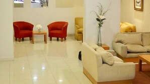 A modern living room with two armchairs, a sofa, a coffee table, and a vase with decorative branches. - Hotel Centro Naval (Buenos Aires)